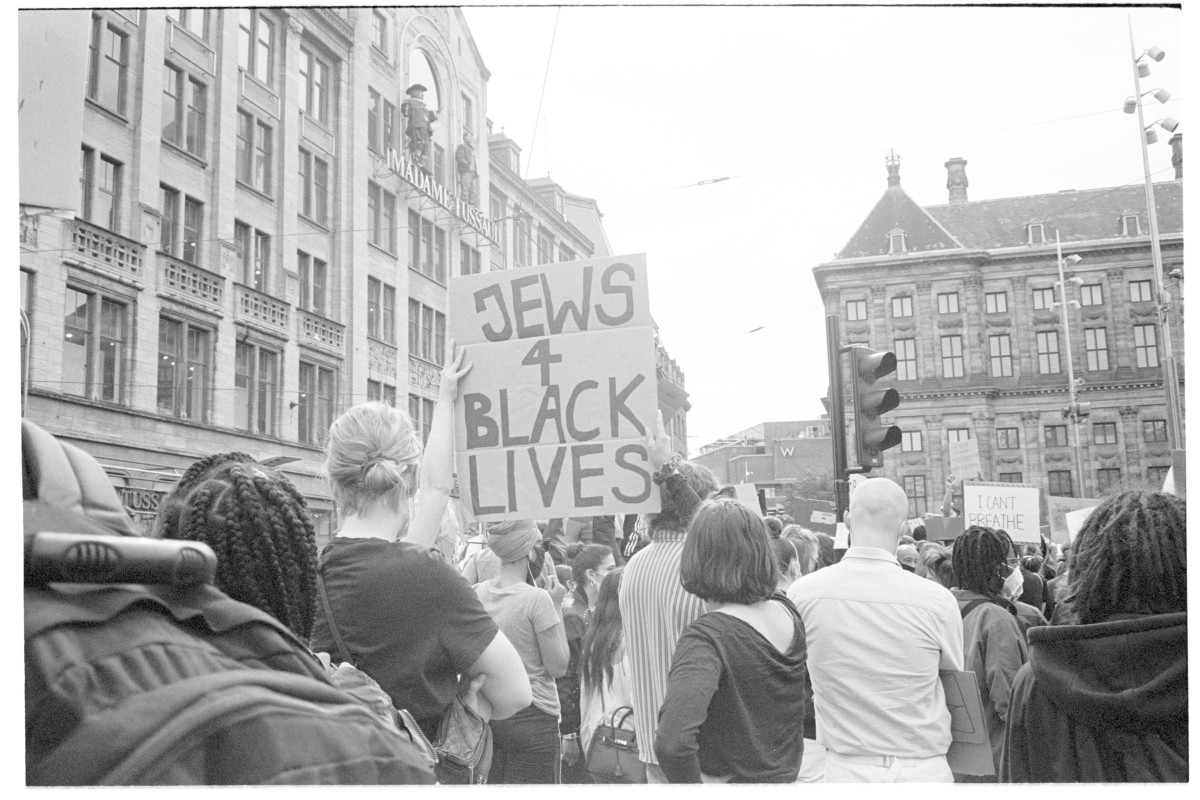 : Crowd at a city protest with a person holding a sign reading 'JEWS 4 BLACK LIVES'