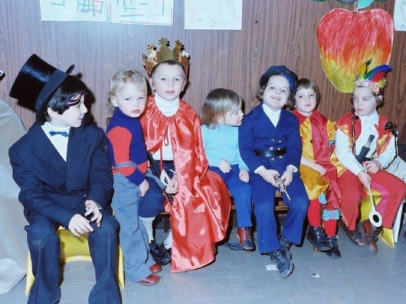 Kinder auf einer Bank sitzend, verkleidet zu Purim