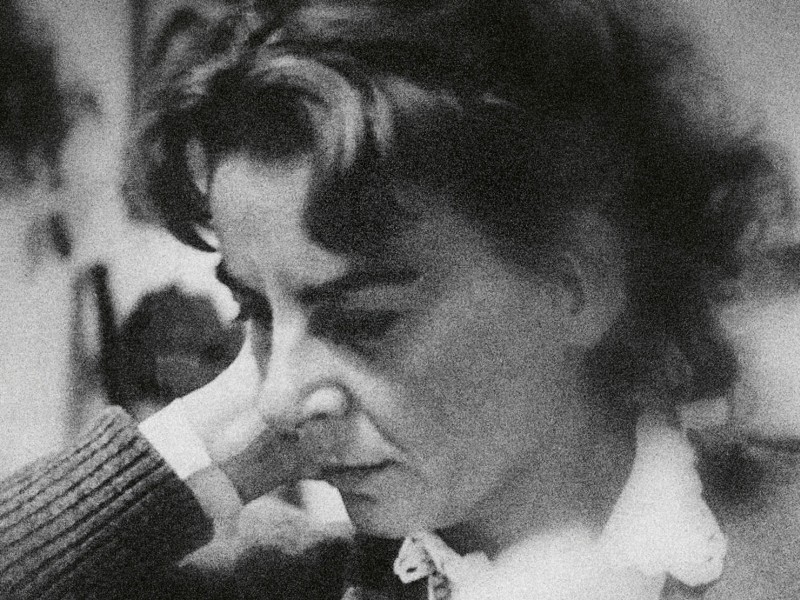 Schwarz-weiß-Porträt einer nachdenklichen Frau mit lockigem Haar, die den Kopf auf die Hand stützt. Text: ‚FRIEDL BENEDIKT‘, ‚WARTE IM SCHNEE‘, ‚VOR DEINER TÜR‘