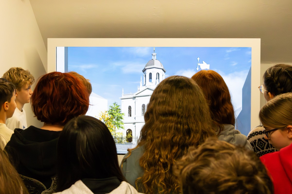 Jugendliche vor virtuellem Museumsbild: Rückansicht einer Gruppe von Jugendlichen, die einen virtuellen Blick auf ein historisches weißes Gebäude mit Kuppel und blauem Himmel werfen