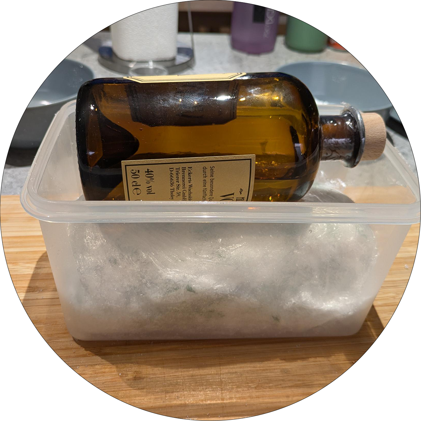 Braune Glasflasche mit Korkverschluss liegt auf einer in Frischhaltefolie eingewickelten Lachsportion in einer transparenten Plastikbox auf einem Holzbrett